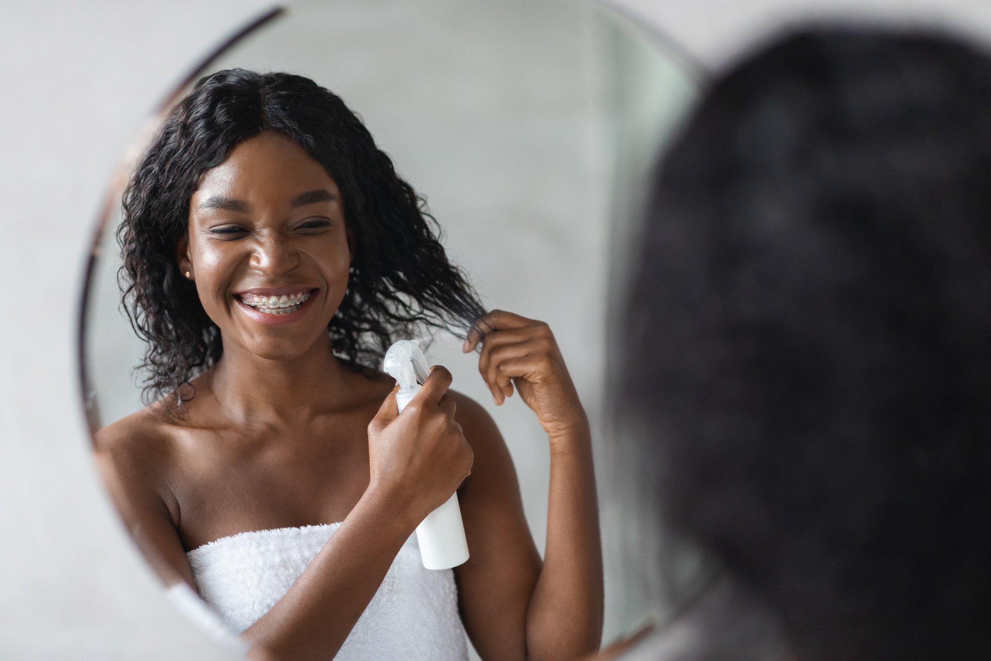 Happy Young Black Woman Using Hair Spray